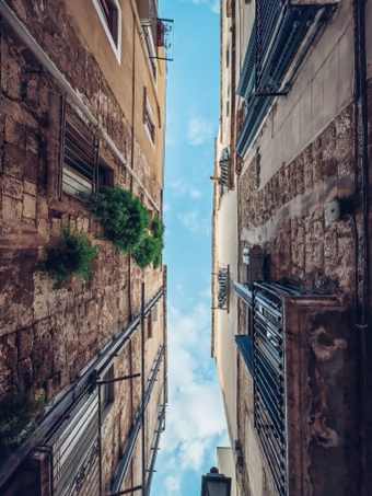 A low angle view of a narrow street between buildings

Description automatically generated