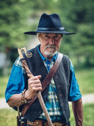 A person in a hat holding a cane

Description automatically generated